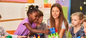 Teacher guiding children in group play, supporting social skill development in children with autism.