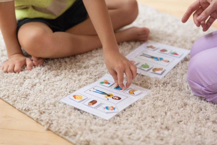 Child using visual schedule cards during ABA therapy to learn antecedent strategies in ABA.