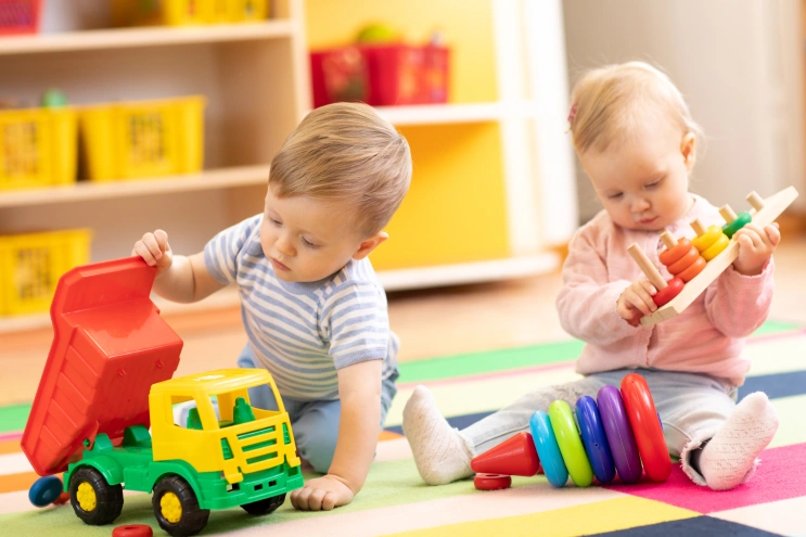 Two toddlers engage in parallel play in autism by playing side by side with toys without direct interaction.