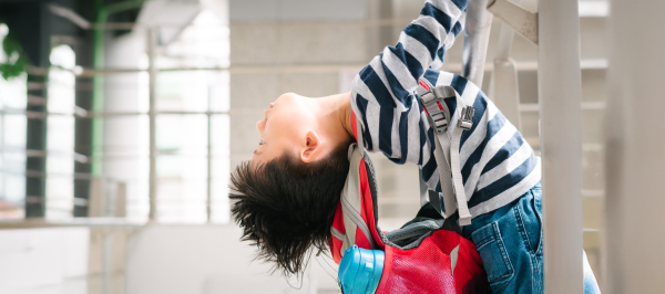 Child leaning back and stretching with a backpack, an example of stimming in children with autism through movement and sensory seeking.
