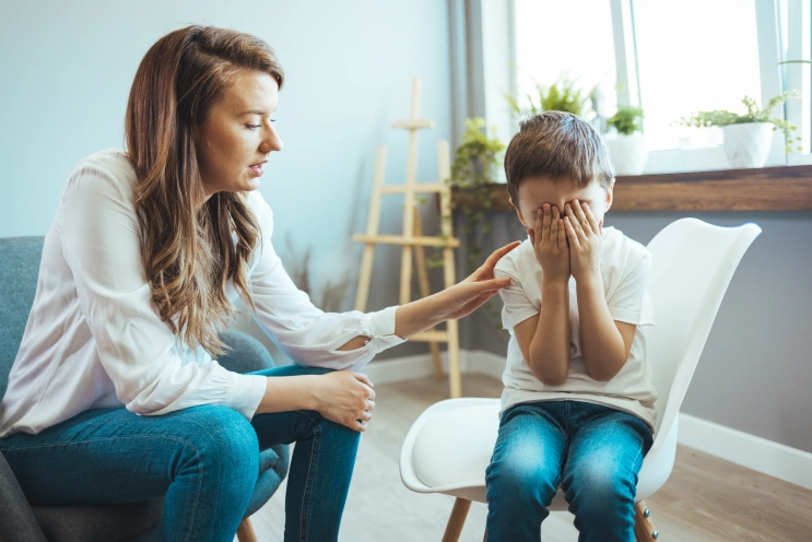 Parent using calming strategies for kids with autism by sitting close and offering gentle support during a stressful moment.